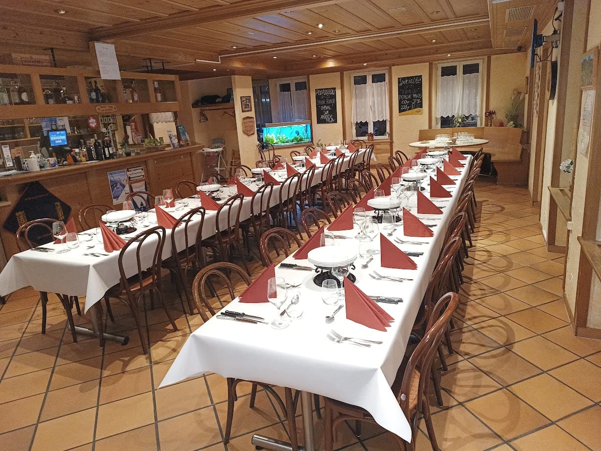 Longue table de banquet dressée de blanc et de rouge dans la salle de l'auberge